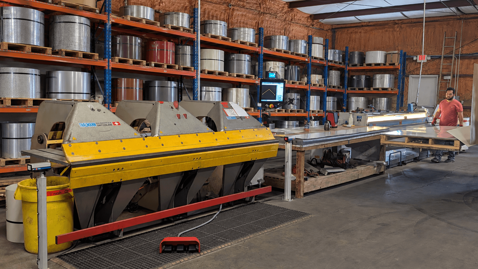 The full Thalmann bending line on the AFS shop floor, coil stock racked behind it and a technician handling formed metal